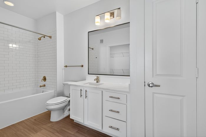 Modern bathroom with elegant white cabinetry, sleek fixtures, and a full tiled shower and bathtub.
