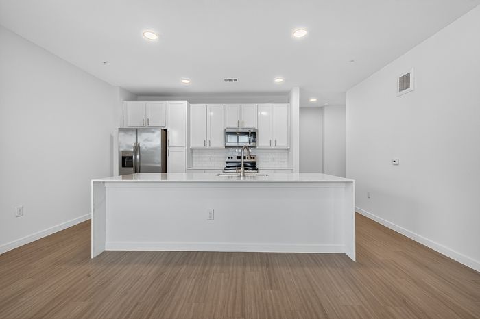 Modern kitchen with sleek white cabinetry, stainless steel appliances, and a spacious island, perfect for culinary enthusiasts.