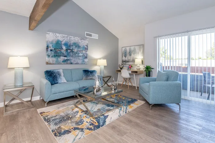 Charming living room with modern blue decor, abstract art, and a cozy seating area, enhancing natural light through large sliding doors.