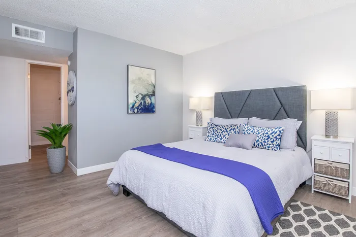 Inviting bedroom with modern decor featuring a cozy bed, stylish gray headboard, vibrant blue accents, and elegant lighting.