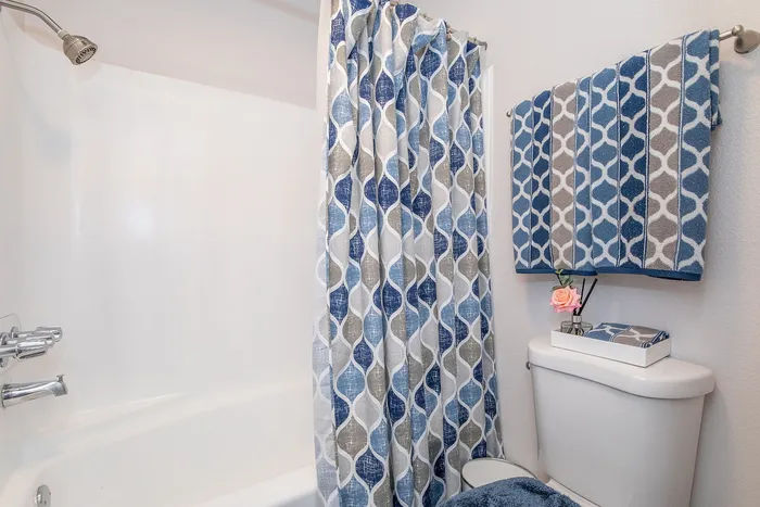 Elegant bathroom with modern blue and gray patterned shower curtain and matching towels, featuring a cozy ambiance.