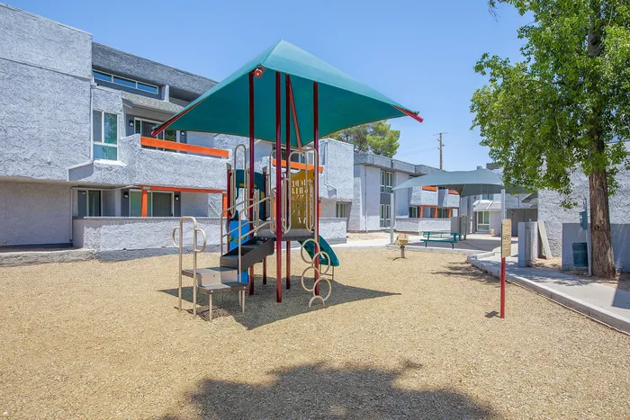Modern apartment community featuring a vibrant playground with colorful equipment surrounded by well-maintained buildings, offering a family-friendly living environment.