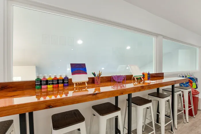Chic and vibrant art station with colorful paints, miniature easels, and stylish stools, ideal for creative inspiration.