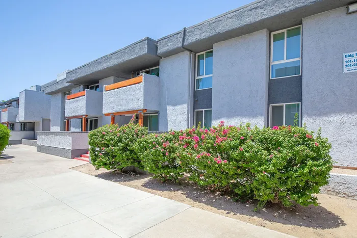 Modern apartment complex with stylish gray facade, vibrant foliage, and inviting balconies.