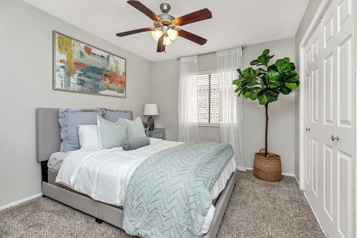 Chic bedroom with elegant decor, featuring a plush bed, stylish art piece, and a lush indoor plant enhancing the tranquil atmosphere.