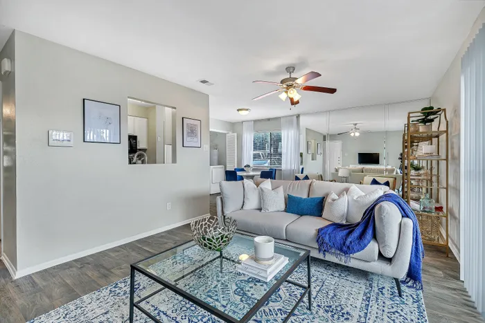Elegant living room with stylish decor, featuring a neutral-toned sofa with vibrant blue accents, glass coffee table, and a cozy atmosphere perfect for relaxation.