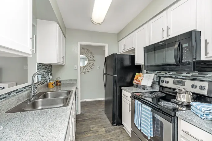 Modern kitchen with sleek white cabinets, stainless steel sink, and stylish appliances. Elegant backsplash adds a contemporary touch.