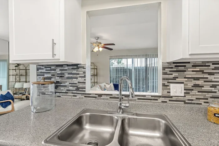 Modern kitchen with sleek countertops, stylish backsplash, and bright open living area.