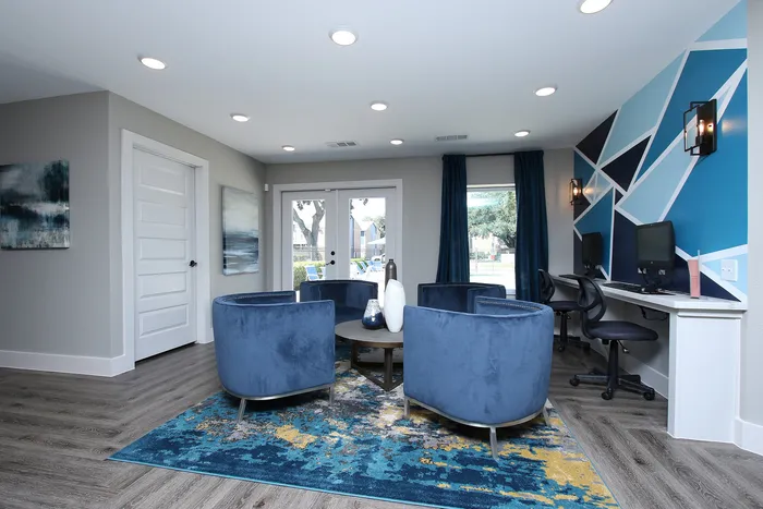 Chic and modern lounge area with plush blue chairs, vibrant geometric accent wall, and elegant wood flooring, perfect for relaxation and work.