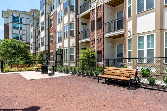 Elegant multi-story apartment complex with modern architecture, lush landscaping, and inviting outdoor seating area.