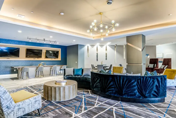 Luxurious modern lounge featuring plush seating, stylish decor, and dual mounted TVs, perfect for entertainment and relaxation.
