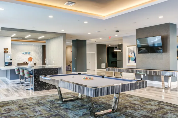 Elegant communal lounge with a stylish billiards table, modern bar seating, and vibrant contemporary artwork.
