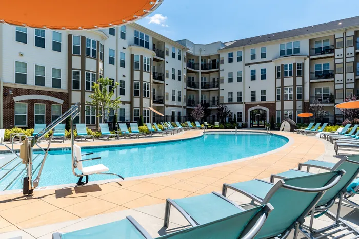 Luxurious apartment complex with a stunning pool area, stylish lounge chairs, and modern architecture. Perfect blend of relaxation and elegance.