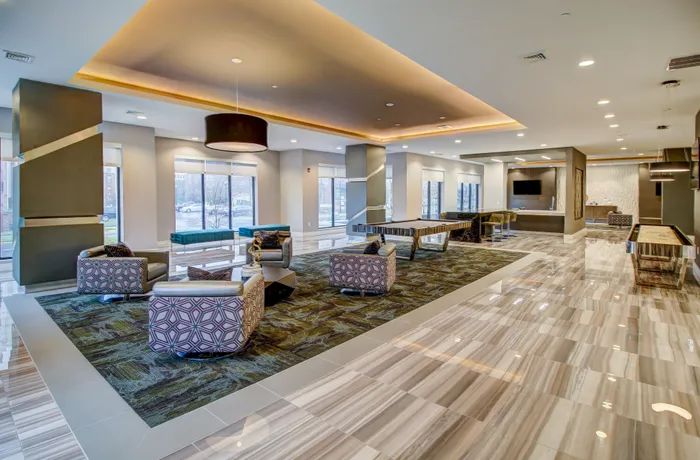 Luxurious and spacious lounge with modern seating areas, elegant recessed lighting, and polished marble-like floors, perfect for relaxation and gatherings.