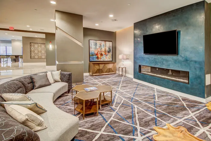 Luxurious apartment lounge with modern decor, featuring a chic curved sofa, abstract art, and an elegant fireplace.