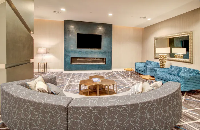 Luxurious living room showcasing a modern curved sofa, elegant blue accents, and a sleek fireplace under a flat-screen TV.