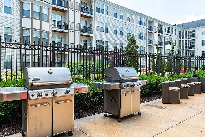 Chic apartment complex featuring modern outdoor grills and comfortable seating, perfect for gatherings and relaxation.