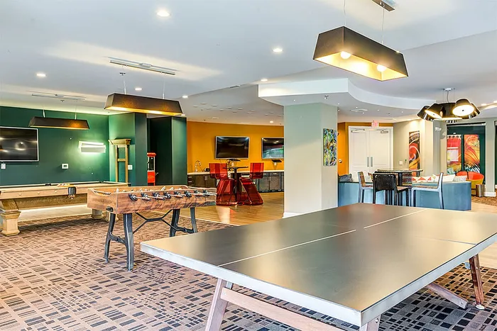 Vibrant communal game room featuring a foosball table, table tennis, and cozy seating areas, perfect for socializing and leisure.
