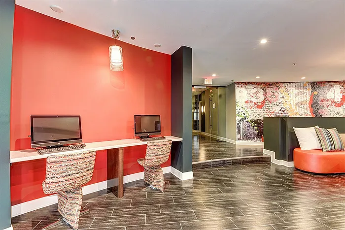 Modern communal workspace with vibrant red accent wall, stylish seating, and sleek flooring, perfect for productivity and creativity.