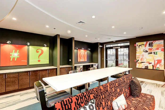 Trendy modern lounge featuring colorful abstract art, stylish seating, and communal workspaces, perfect for social gatherings.