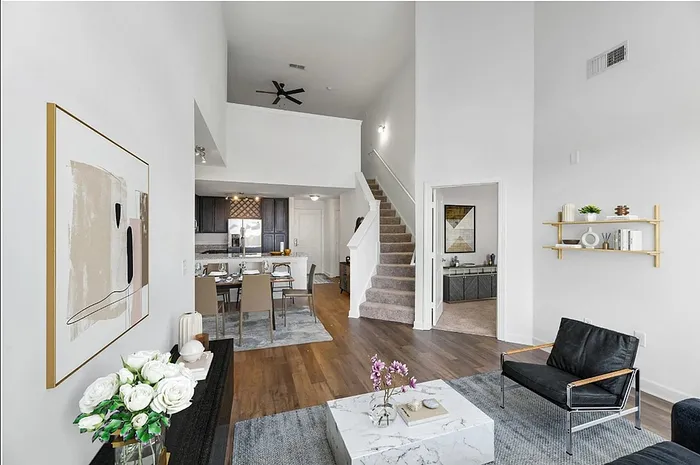 Chic living area with high ceilings, modern staircase, and elegant kitchen, perfect for stylish entertaining.