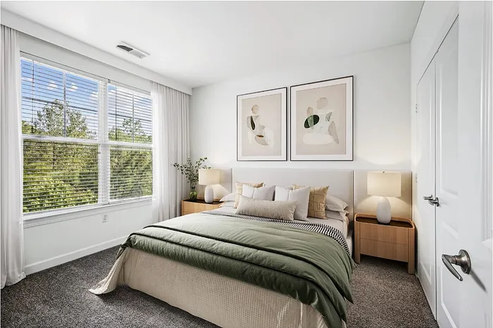 Bright and elegant bedroom featuring a lush green comforter, modern decor, and ample natural light through large windows.