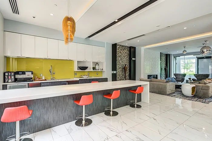 Modern open-concept apartment with sleek kitchen, vibrant orange chairs, and spacious living area with stylish decor.