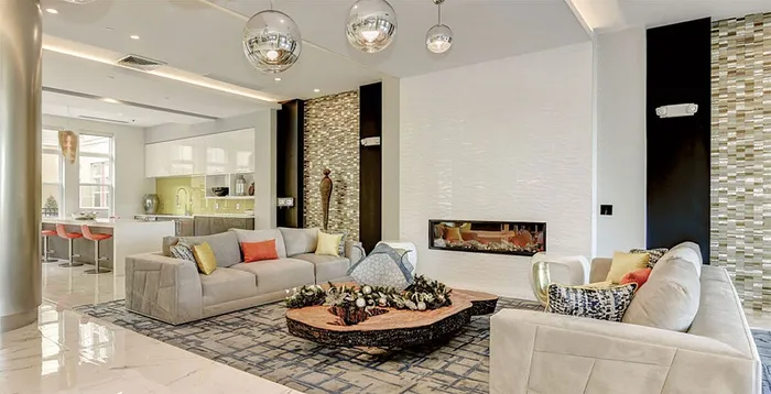 Luxurious open-concept living room with modern decor, elegant fireplace, and stylish kitchen area featuring vibrant accents and sleek furniture.
