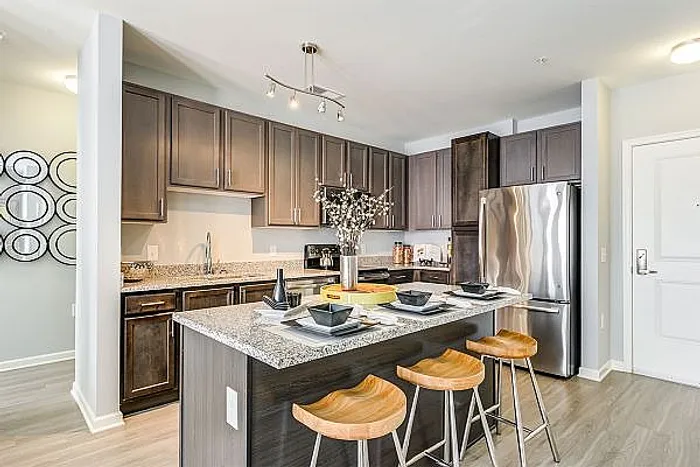 Chic kitchen with elegant dark wood cabinets, granite countertops, and modern stainless steel appliances, complemented by stylish bar stools and contemporary decor.