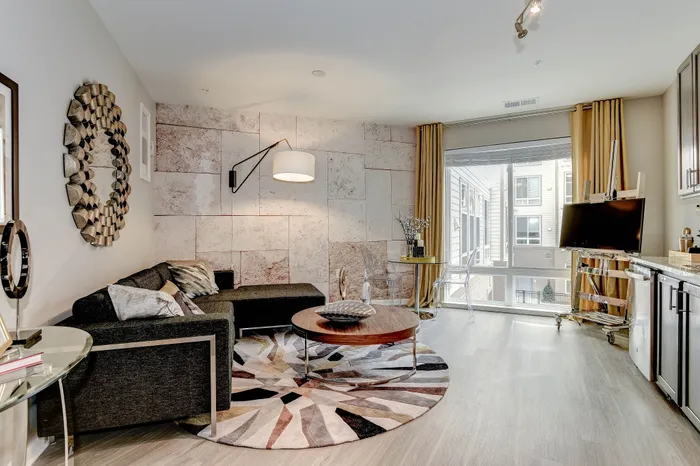 Chic modern living room with stylish L-shaped sofa, geometric rug, and large window for natural light.