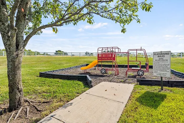 Charming outdoor playground with a colorful fire engine-themed play structure under a lush green tree, perfect for family fun and relaxation.