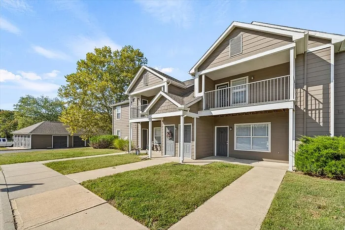 Inviting townhouse exterior with charming balconies, lush green lawns, and a peaceful suburban setting.