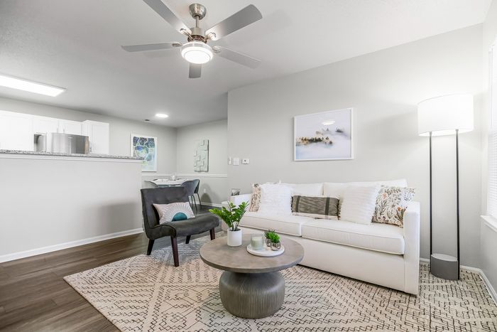 Contemporary open-concept living area showcasing a cozy white sofa, elegant decor, and sleek kitchen counter in a modern apartment.