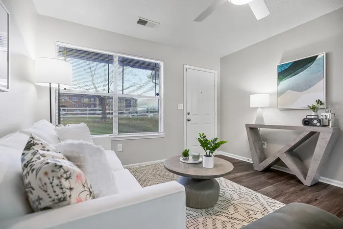 Bright living room with modern decor, featuring a white sofa, stylish coffee table, and a contemporary art piece, creating a welcoming ambiance.