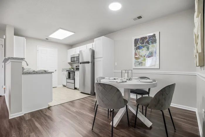 Contemporary kitchen and dining area with sleek stainless steel appliances, elegant dining set, and modern artwork.