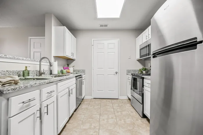 Modern kitchen boasting sleek stainless steel appliances, elegant granite countertops, and crisp white cabinetry, perfect for culinary enthusiasts.