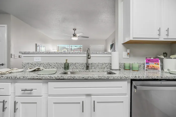Bright and modern kitchen with sleek granite countertops, stainless steel appliances, and chic white cabinetry.