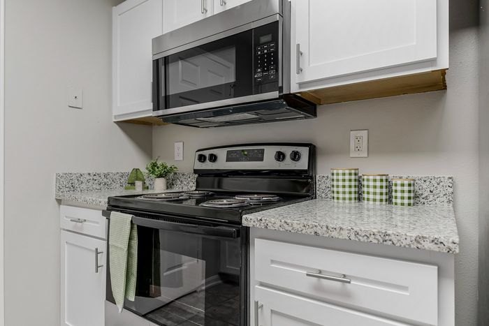 Modern kitchen showcasing sleek black appliances, elegant granite countertops, and stylish white cabinetry with vibrant green accents.
