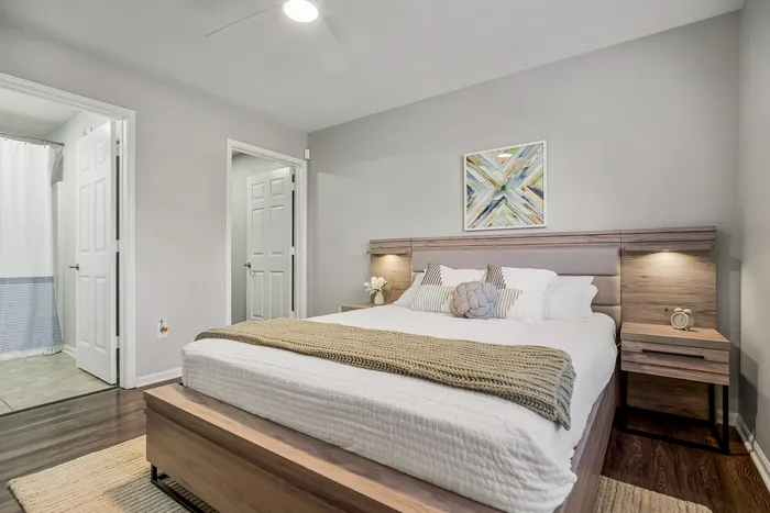 Bright and inviting bedroom with stylish decor, cozy lighting, modern wood accents, and an en-suite bathroom.