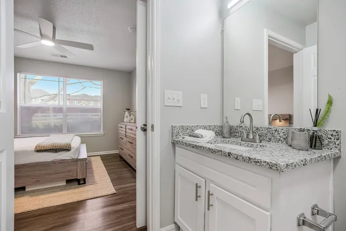 Modern bedroom and bathroom combo with sleek granite countertops and abundant natural light, creating a bright and inviting space.