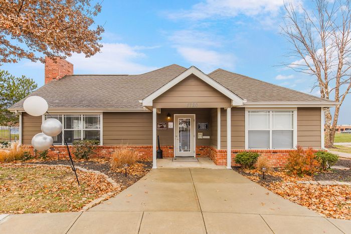 Charming single-story office building with a welcoming porch, surrounded by autumn foliage and decorative balloons.