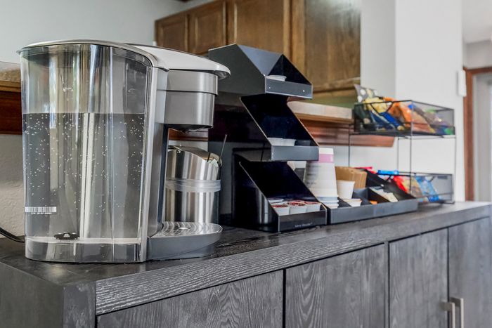Modern kitchen setup with sleek water dispenser, stylish storage containers, and a variety of snack options on a contemporary wooden counter.