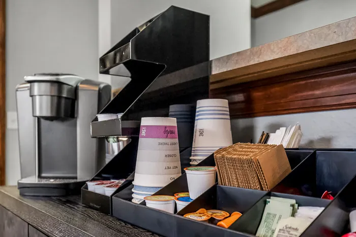 Modern coffee station with a sleek espresso machine, stylish cup dispenser, and organized condiment trays.
