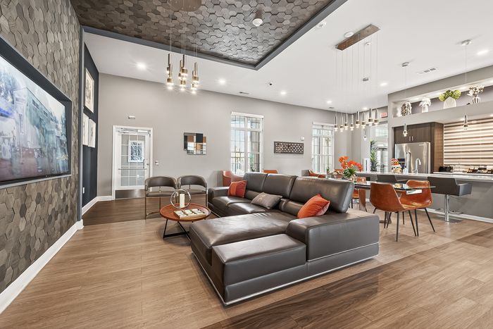 Sophisticated open-plan living and dining area with modern leather sectional, chic lighting, and a spacious kitchen, perfect for entertaining.