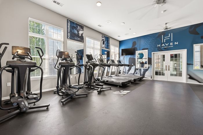 Modern fitness center featuring state-of-the-art exercise machines, bright natural lighting, and motivational decor at Haven at Bellaire.