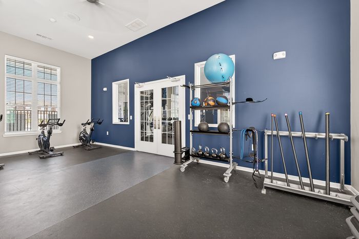 Modern fitness room with vibrant blue accent wall, featuring exercise bikes, weights, and gym equipment for a dynamic workout experience.