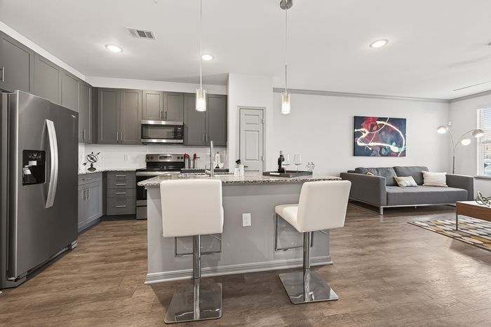 Modern open-concept kitchen and living area with sleek gray cabinetry, stylish island seating, and contemporary decor.