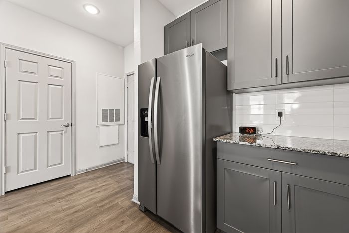 Sleek modern kitchen with stainless steel fridge, elegant gray cabinetry, and wood flooring inviting a sophisticated touch.