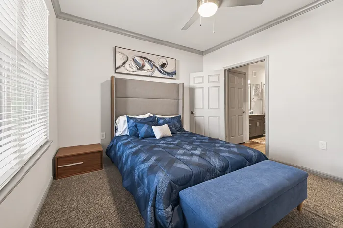 Elegant bedroom with plush blue bedding, modern artwork, and abundant natural light enhancing the cozy ambiance.