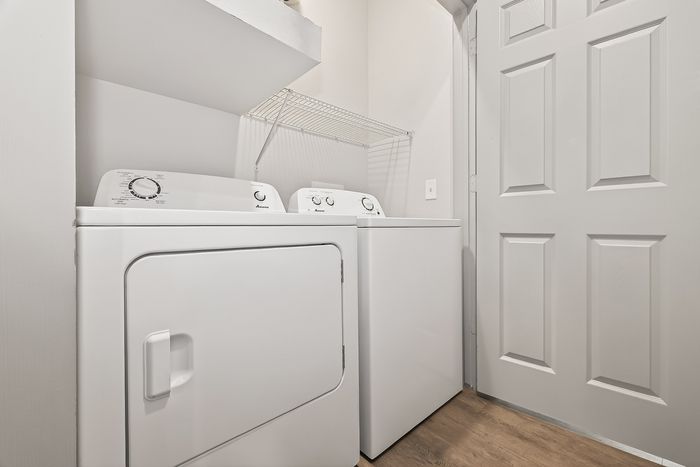 Contemporary utility room featuring a sleek washer and dryer set alongside a convenient shelving unit.